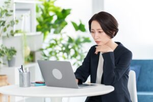パソコンを見ながら考える女性